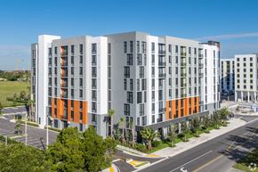 Homestead apartment for rent - A modern multi-story building with orange and grey accents.