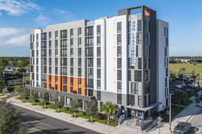 Homestead apartment for rent - A modern multi-story building with a sign that reads "NOW LOW LEASING".