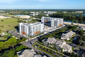 Homestead apartment for rent - A large building with a lot of windows is surrounded by other buildings and trees.