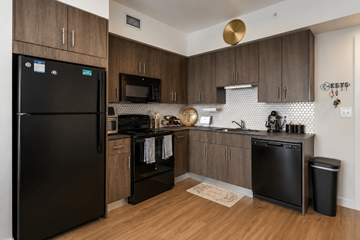 Palmetto Bay apartment for rent - A black fridge sits in a kitchen with wooden cabinets and a black dishwasher.