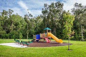 Brooksville apartment for rent - A playground with a yellow slide and green benches.