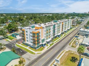Bradenton apartment for rent - A multi-story apartment building with a green roof is surrounded by a road and other buildings.