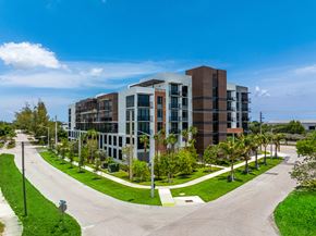 Deerfield Beach apartment for rent - A modern multi-story building with a parking lot in front.
