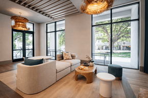 Miami apartment for rent - A modern living room with a large window and a wooden coffee table.