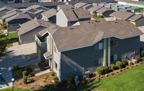 Fontana apartment for rent - A large grey house with a brown roof and a green lawn in front.