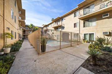 Van Nuys apartment for rent - A sunny day at a residential complex with a pool and a fence.