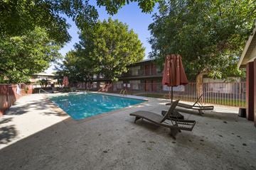 Buena Park apartment for rent - A pool surrounded by trees and chairs.