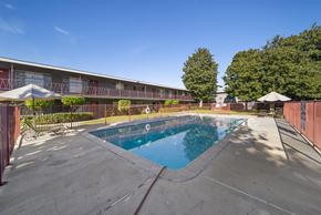 Buena Park apartment for rent - A swimming pool in front of a building with a red fence.