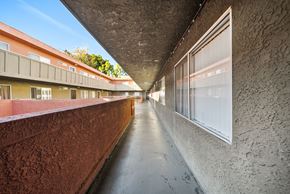 North Hills apartment for rent - A long hallway with a red wall on the left and a concrete wall on the right.