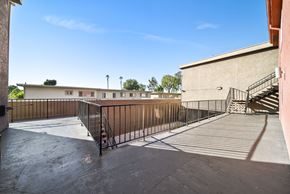 North Hills apartment for rent - A courtyard with a metal railing and a staircase leading to a building.