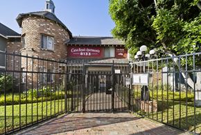 Van Nuys apartment for rent - A black iron gate leads to a brick building with a sign that says Casa Royal Apartments.