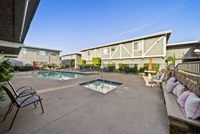Van Nuys apartment for rent - A pool surrounded by chairs and a fence.