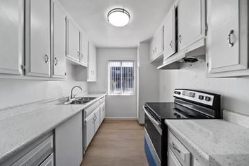 North Hills apartment for rent - A kitchen with white cabinets and a black stove top oven.
