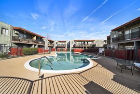 North Hills apartment for rent - A swimming pool surrounded by a wooden deck and buildings.