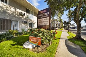Van Nuys apartment for rent - A sign for 16025 Courtyard Apartments is displayed in front of a building.
