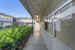 Van Nuys apartment for rent - A long concrete walkway leads to a building with a balcony.