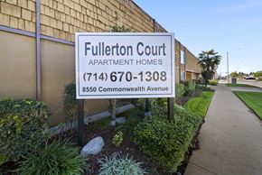 Buena Park apartment for rent - A sign for Fullerton Court Apartment Homes stands in front of a building.