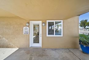 Buena Park apartment for rent - A beige building with a white door and a sign on the wall.