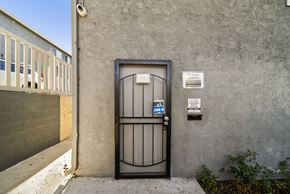 Los Angeles apartment for rent - A black gate with a blue sign that says "OPEN" in front of a grey wall.