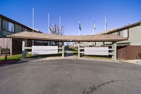 Tehachapi apartment for rent - A building with a covered walkway and flags on top.