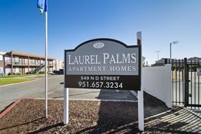 Perris apartment for rent - A sign for Laurel Palms Apartment Homes stands in front of a building.