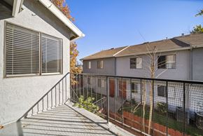 Hemet apartment for rent - A balcony with a metal railing and a tree in the background.