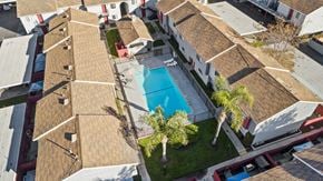 Hemet apartment for rent - A swimming pool is surrounded by palm trees and a grassy area.