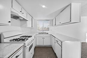 Hemet apartment for rent - A white kitchen with a stove and cabinets.
