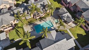 Hemet apartment for rent - A bird's eye view of a neighborhood with a pool and palm trees.