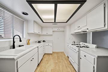Hemet apartment for rent - A white kitchen with a black ceiling and wooden floors.
