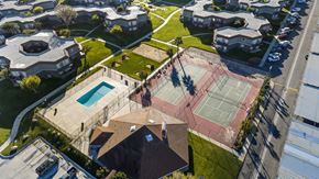 Palmdale apartment for rent - A tennis court is surrounded by a fence and a swimming pool.