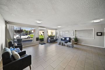 Panorama City apartment for rent - A spacious living room with a black couch and a large window.