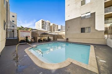 Los Angeles apartment for rent - A small pool with a diving board is surrounded by buildings.