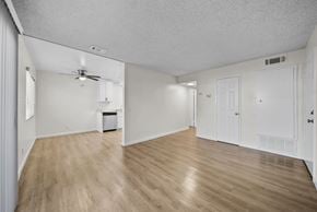 San Bernardino apartment for rent - A spacious room with wooden flooring and white walls.