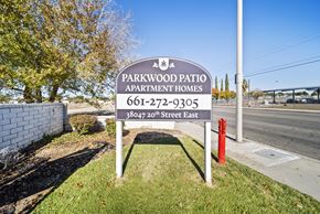 Palmdale apartment for rent - A sign for Parkwood Patio Apartment Homes stands in front of a tree.