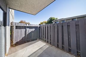 Palmdale apartment for rent - A concrete patio with a grey fence and a white wall.