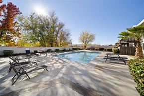 Palmdale apartment for rent - A sunny day at the outdoor pool with trees and a building in the background.