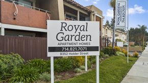 Cypress apartment for rent - A sign for Royal Garden Apartment Homes stands in front of a building.
