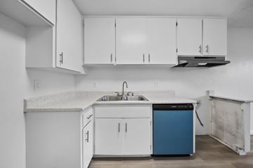 Cypress apartment for rent - A kitchen with white cabinets and a blue dishwasher.