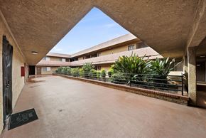 Long Beach apartment for rent - A courtyard with a triangular roof and a fence with plants on it.