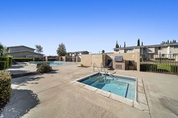 Fontana apartment for rent - A large outdoor swimming pool surrounded by a concrete patio and buildings.