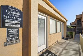 Perris apartment for rent - A leasing office sign is posted on a wall outside a building.