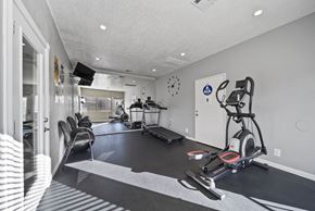 Perris apartment for rent - A modern home gym with a treadmill, elliptical trainer, and other exercise equipment.