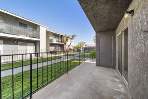 Palmdale apartment for rent - A concrete building with a black fence in front.