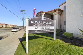 Palmdale apartment for rent - A sign for Royal Palms Apartment Homes stands in front of a building.
