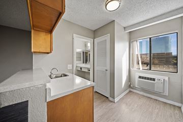 Santa Ana apartment for rent - A kitchen with a white counter top and wooden cabinets.