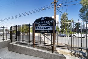 North Hollywood apartment for rent - A sign for Shadowbrooks Apartments is displayed in front of a fence.