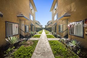 Pacoima apartment for rent - A row of houses with a concrete walkway between them.