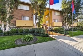 Pacoima apartment for rent - A building with a brown and yellow exterior and a small garden in front.