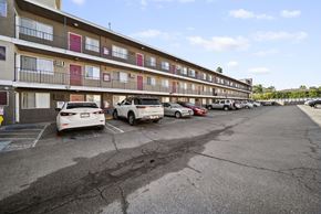 Van Nuys apartment for rent - A parking lot in front of a multi-story apartment building with cars parked.